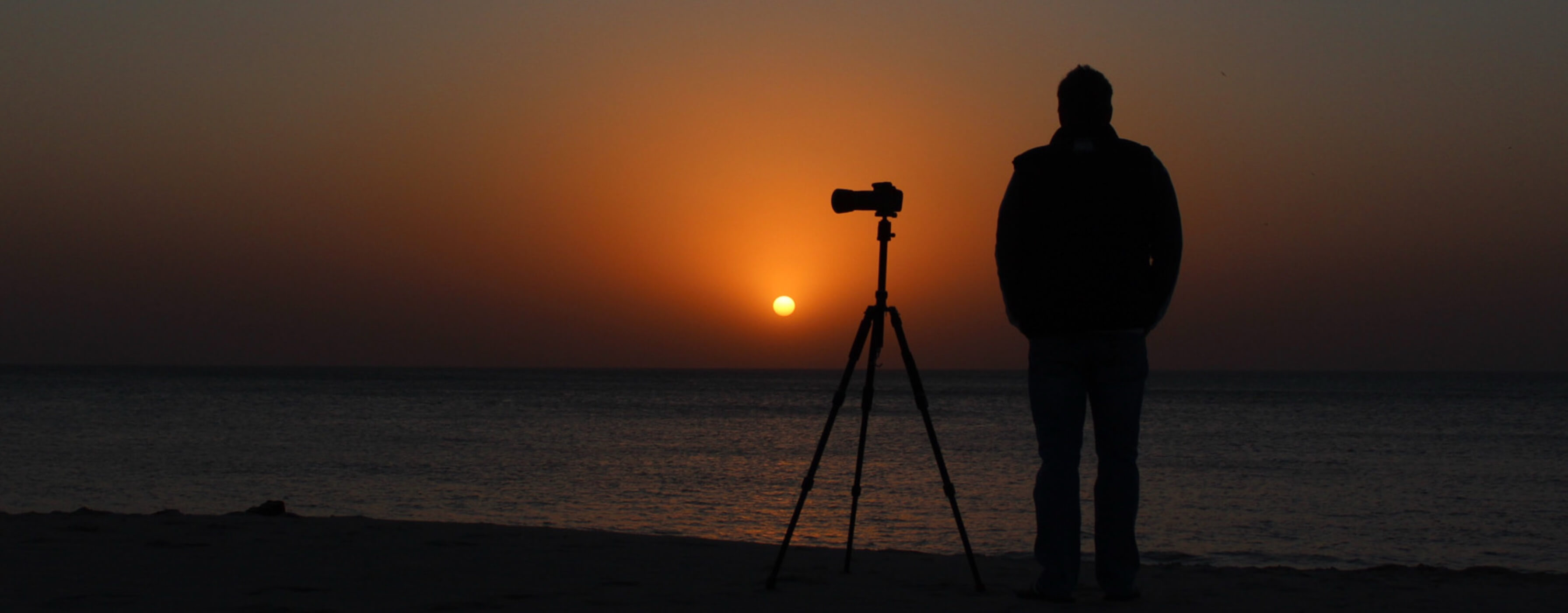 Ein Sonnenuntergang am Meer, ein Mann steht im Mittelpunkt
